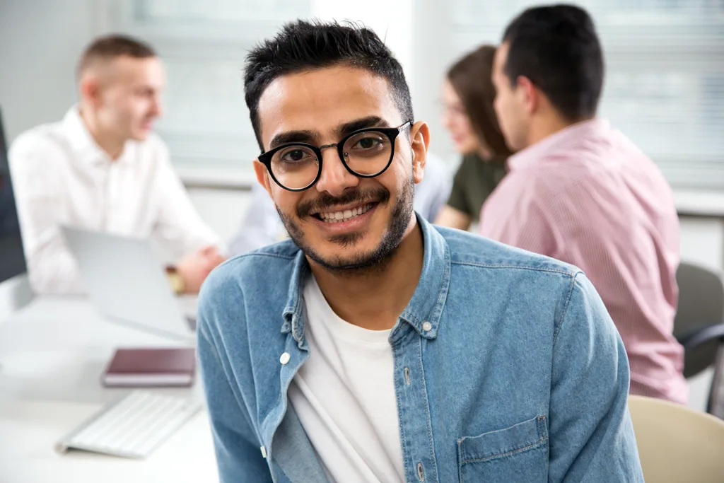Colaborador latino con audífonos concentrado en laptop, adaptándose a distintas dinámicas